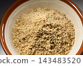 The fine particles of ground sesame seeds spread out in the mortar, a scene of preparation for cooking. 143483520