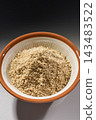 The overall view of ground sesame seeds in a mortar, showing the contrast between the white interior and the brown exterior. 143483522