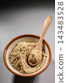 A cooking scene showing white sesame seeds being ground in a mortar with a wooden pestle. 143483528