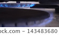 Macro shot of home gas stove burner ignited with steady blue flames. 143483680