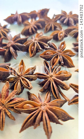 Rich, brown star anise pods photographed in macro detail, highlighting their star shapes, texture and glossy seeds Rich, brown star anise pods photographed in macro detail, highlighting their star shapes, texture and glossy seeds 143483702