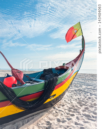 Traditional Portuguese fishing boat on sandy beach with flag Traditional Portuguese fishing boat on sandy beach with flag 143484063