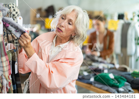 Mature woman customer examine and choose scarf in store Mature woman customer examine and choose scarf in store 143484181