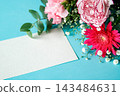 A bouquet of pink and red flowers and a message card on a light blue background. 143484631