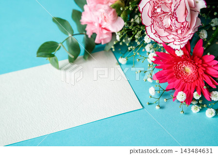 A bouquet of pink and red flowers and a message card on a light blue background. 143484631