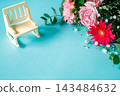 A bouquet of pink and red flowers and a miniature chair against a light blue background. 143484632