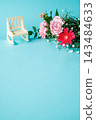 A bouquet of pink and red flowers and a miniature chair against a light blue background. 143484633