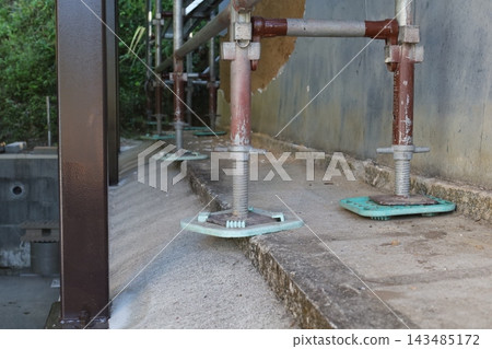 鷹架管路和千斤頂底座沿著翻修施工現場的外牆排列。 鷹架管路和千斤頂底座沿著翻修施工現場的外牆排列。 143485172