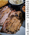 Smoked brisket served with baked beans, creamy mashed potatoes and toast on a casual barbecue plate. Hearty comfort-food meal showcasing tender meat, smoky flavors 143486028