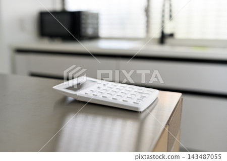 廚房檯面上放著一台白色計算器。 廚房檯面上放著一台白色計算器。 143487055