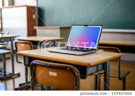 教室桌上擺放著一台筆記型電腦和學習環境。 教室桌上擺放著一台筆記型電腦和學習環境。 143487068