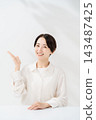 A smiling woman guiding with her palm 143487425