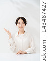 A smiling woman guiding with her palm 143487427