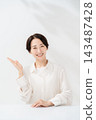 A smiling woman guiding with her palm 143487428