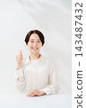A woman smiling with a thumb 143487432