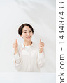 A smiling woman giving a thumbs-up with both hands. 143487433