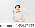 A smiling woman explains while holding up her index finger. 143487435