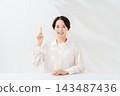 A smiling woman explains while holding up her index finger. 143487436