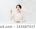 A smiling woman explains while holding up her index finger. 143487437