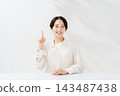 A smiling woman explains while holding up her index finger. 143487438