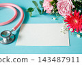 A message card for medical and welfare purposes: A blank card surrounded by a pink bouquet of flowers and a stethoscope. 143487911
