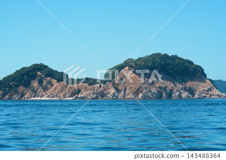一座綠樹成蔭的小島,擁有裸露的岩壁和蔚藍的大海。 一座綠樹成蔭的小島,擁有裸露的岩壁和蔚藍的大海。 143488364