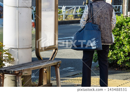 一位老婦人購物後在公車站等車。 一位老婦人購物後在公車站等車。 143488531