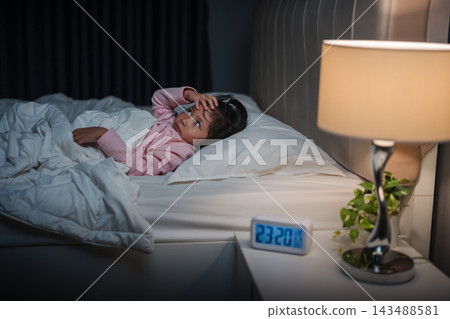 tired preschool child girl having trouble sleeping and headache in bed late at night, insomnia concept tired preschool child girl having trouble sleeping and headache in bed late at night, insomnia concept 143488581