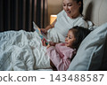 happy mother read story in the book for preschool child girl in bed at night 143488587