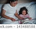 happy mother read story in the book for preschool child girl in bed at night 143488588
