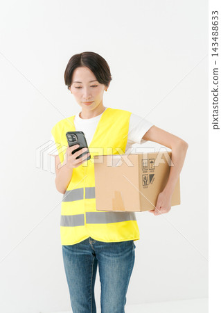 女送貨員抱著一個紙箱 女送貨員抱著一個紙箱 143488633