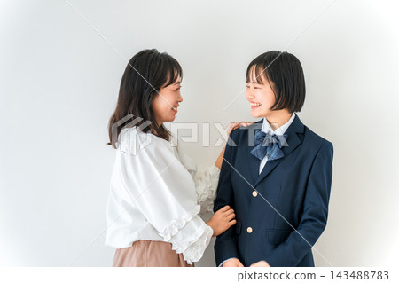 一位母親面帶微笑，站在身穿校服的高中女兒身邊。國中生即將入學或升上下一年級。 143488783