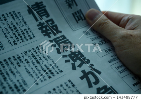 一手拿著一份報紙,報紙上刊登著一篇關於資料外洩的文章。 一手拿著一份報紙,報紙上刊登著一篇關於資料外洩的文章。 143489777