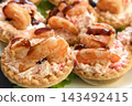 Shrimp tartlets are arranged on a plate. Each tartlet is filled with creamy mixture and topped with shrimp and sauce. Perfect for a gathering or event 143492415