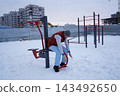 Active mature guy training on outdoor workout machine during a cold snowy day for healthy lifestyle concept. 143492650