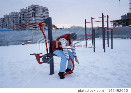 Active mature guy training on outdoor workout machine during a cold snowy day for healthy lifestyle concept. Active mature guy training on outdoor workout machine during a cold snowy day for healthy lifestyle concept. 143492650
