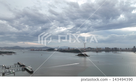 從空中俯瞰廈門灣，可以看到島嶼、碼頭和遠處的城市天際線。 143494390