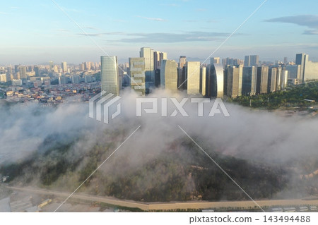 清晨,中國廈門的天際線在雲層之上拍攝的空拍照片(廣角)。 清晨,中國廈門的天際線在雲層之上拍攝的空拍照片(廣角)。 143494488