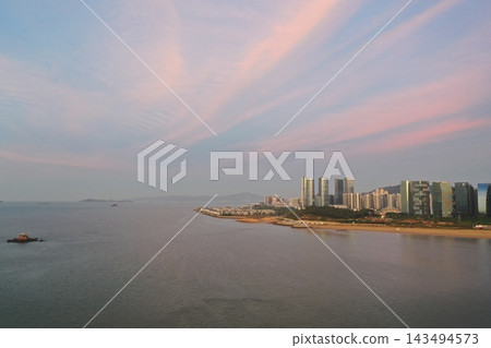 從空中俯瞰廈門沿海天際線,夕陽染成粉紅色。 從空中俯瞰廈門沿海天際線,夕陽染成粉紅色。 143494573