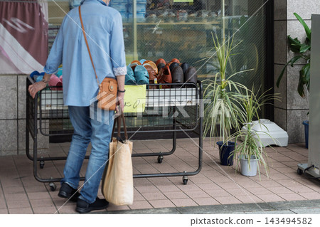 A senior man browsing products in a shoe shop. A senior man browsing products in a shoe shop. 143494582