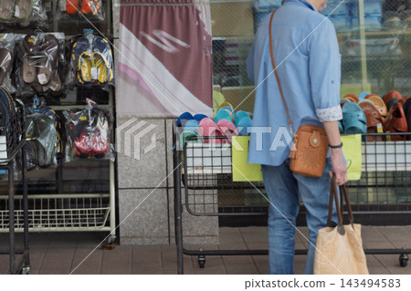 A senior man browsing products in a shoe shop. A senior man browsing products in a shoe shop. 143494583