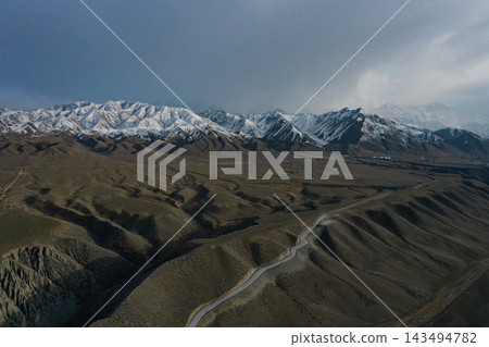新疆,乾旱高原上聳立著白雪皚皚的山脈,道路縱橫交錯。 新疆,乾旱高原上聳立著白雪皚皚的山脈,道路縱橫交錯。 143494782
