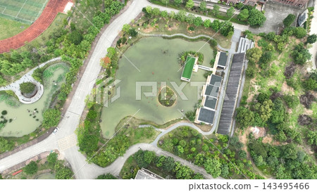 從空中俯瞰城市公園,公園中央有一個池塘和運動跑道。 從空中俯瞰城市公園,公園中央有一個池塘和運動跑道。 143495466