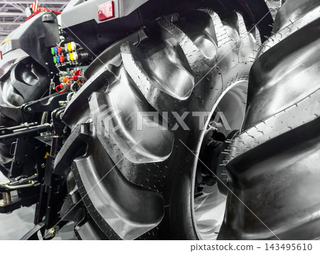 Tractor tire details showcased at an agricultural equipment exhibition in a large indoor venue Tractor tire details showcased at an agricultural equipment exhibition in a large indoor venue 143495610