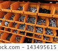 Display of various metal fasteners organized in orange bins on a shelf in a hardware store 143495615