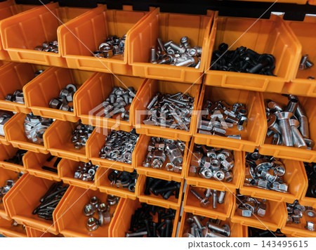 Display of various metal fasteners organized in orange bins on a shelf in a hardware store Display of various metal fasteners organized in orange bins on a shelf in a hardware store 143495615