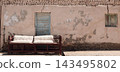 Old wooden outdoor sofa standing beside a weathered house in Egypt, featuring aged furniture, rustic character and authentic traditional architecture 143495802
