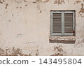 Authentic weathered sand-colored wall with an old distressed window in Egypt, featuring peeling paint, aged texture and rustic traditional architecture 143495804