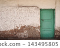 Old green wooden doors set in a weathered brick wall of a traditional Egyptian house, featuring aged surfaces, rustic architectural details and authentic local character 143495805