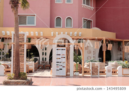 Stylish outdoor cafe in a colorful tourist district of Egypt, featuring creative design, vibrant surroundings and an inviting atmosphere for dining and relaxation Stylish outdoor cafe in a colorful tourist district of Egypt, featuring creative design, vibrant surroundings and an inviting atmosphere for dining and relaxation 143495809